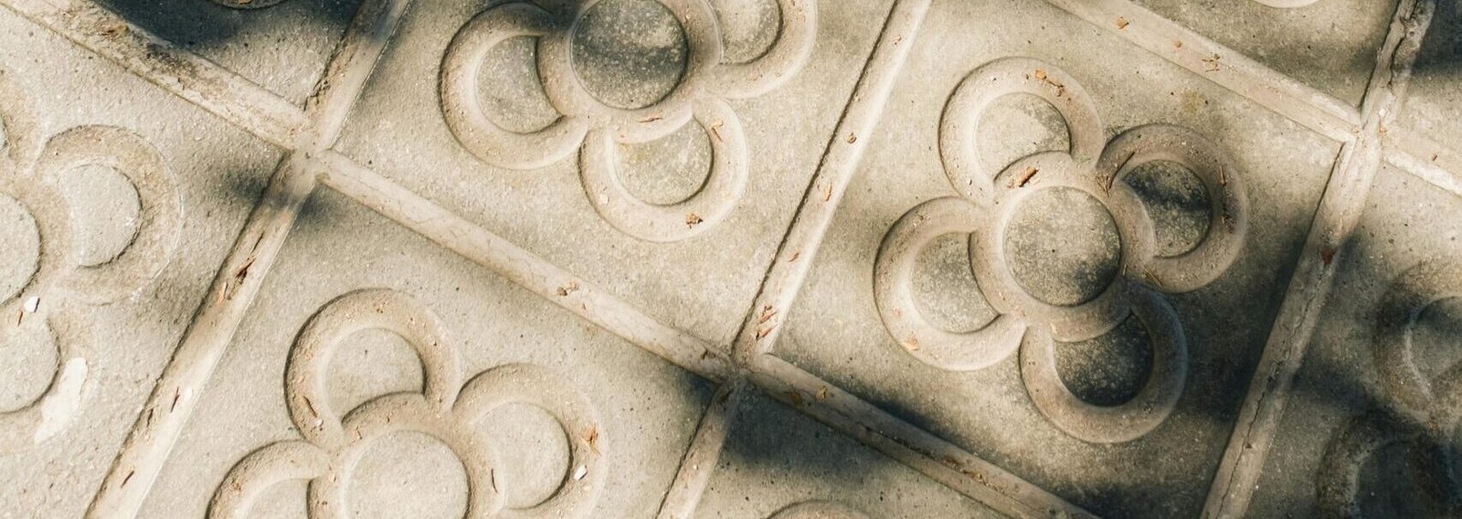 Decorative concrete tiles with shadows on a Barcelona sidewalk.